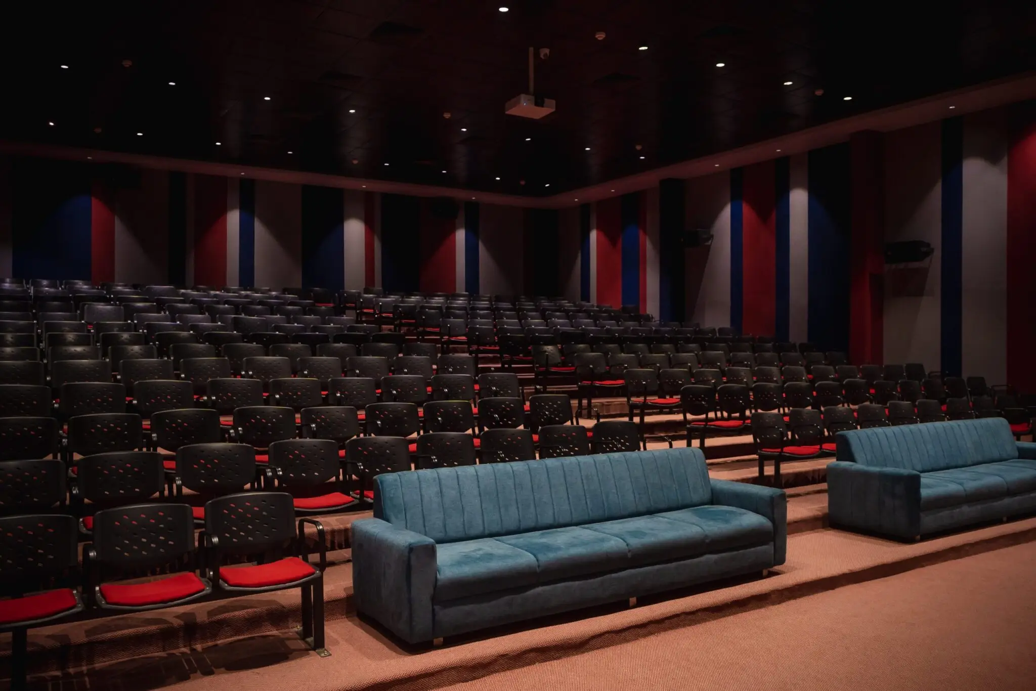 Large modern auditorium with tiered seating and comfortable couches at a top MBA college in Mumbai, designed for seminars, conferences and student events.